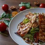 Delicious grilled chicken salad served with fresh tomatoes and walnuts on the side.