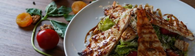 Delicious grilled chicken salad served with fresh tomatoes and walnuts on the side.