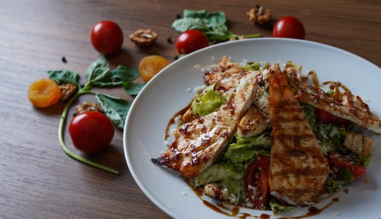 Delicious grilled chicken salad served with fresh tomatoes and walnuts on the side.